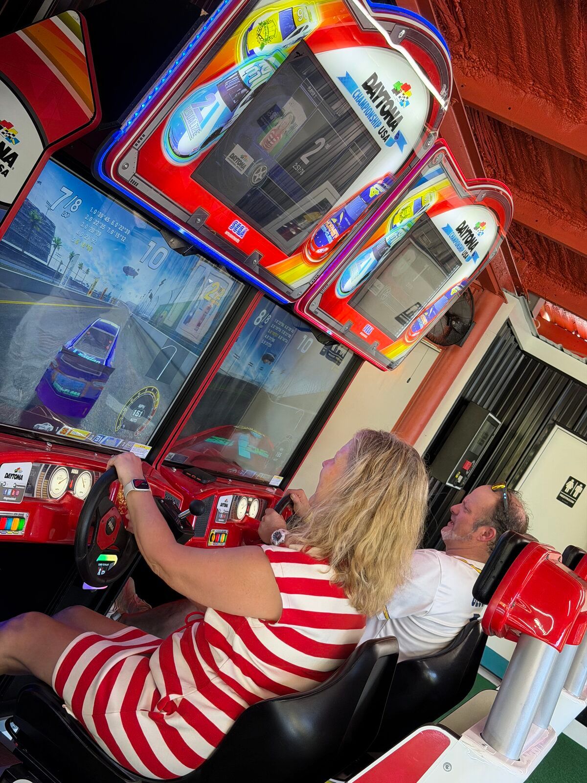 Two guests racing side by side on the Daytona driving cabinets at Platform 32.