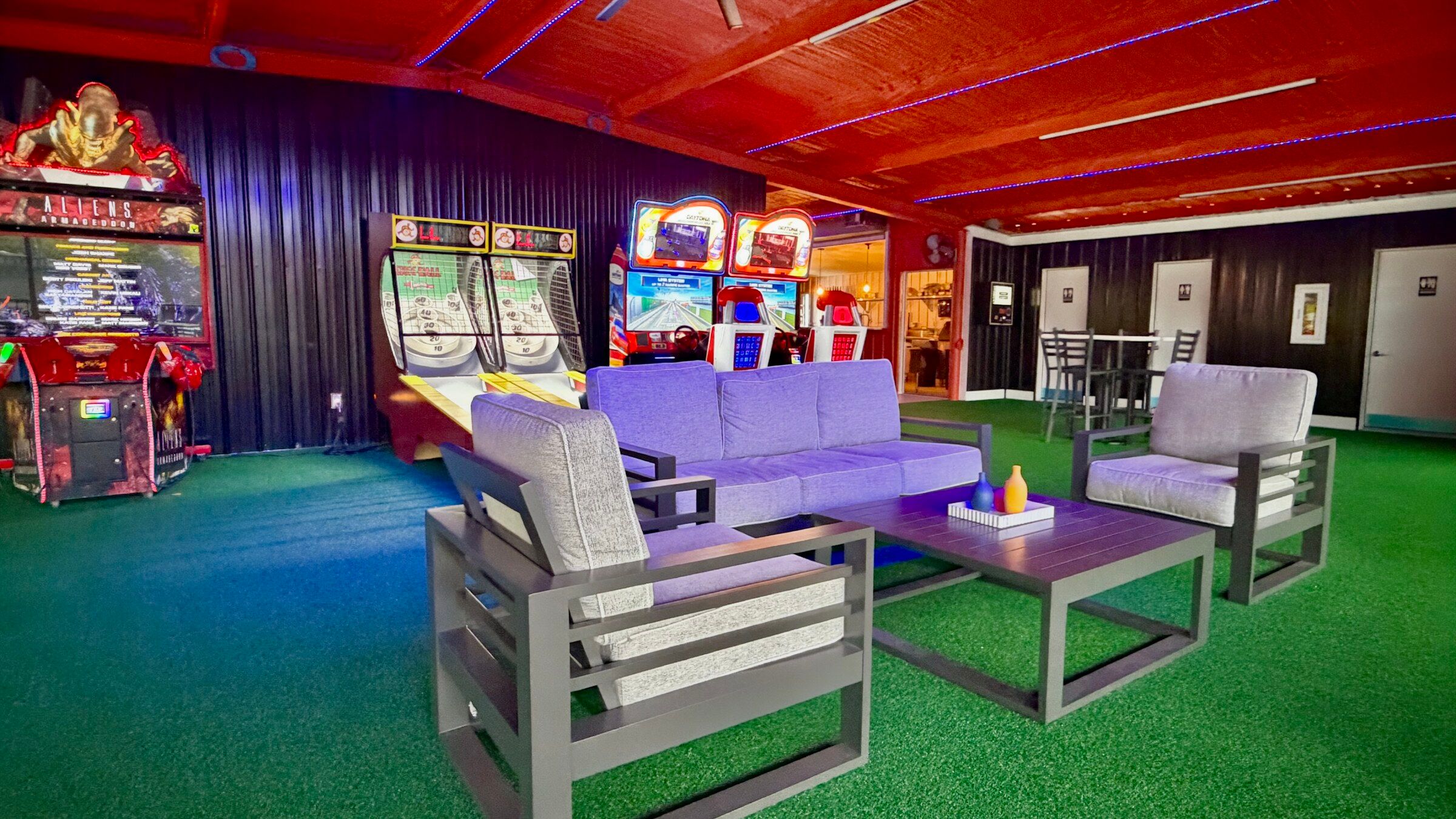 Arcade cabinets and skee-ball lanes at Platform 32 with lounge seating on green turf in front of them
