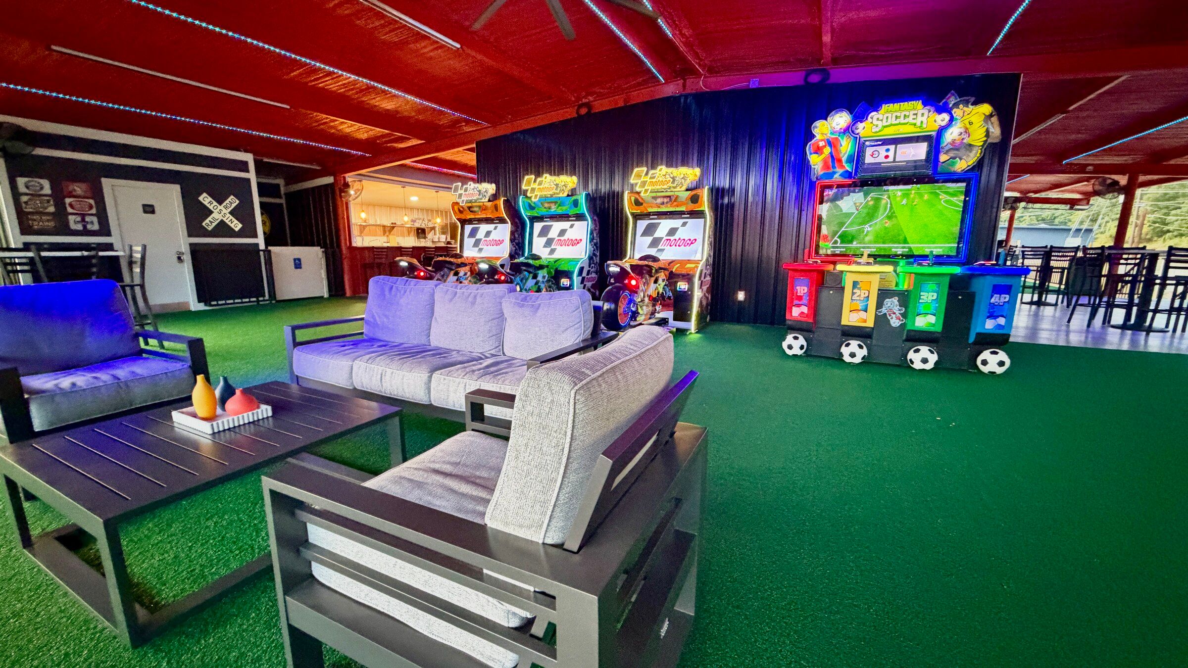 Three MotoGP riding cabinets and a large Fantasy Soccer screen at Platform 32, seen past a lounge sofa