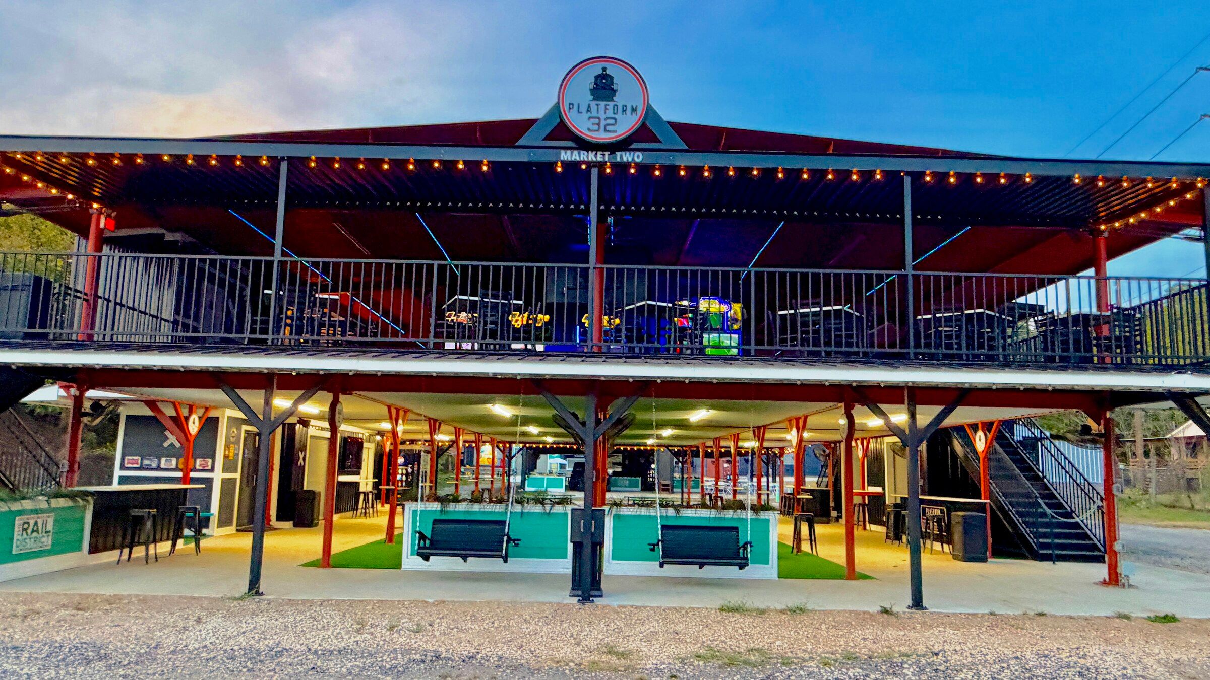 Platform 32 lit at blue hour, string lights along both decks and porch swings under the canopy.